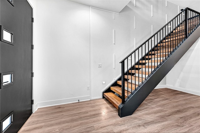 staircase with a towering ceiling and hardwood / wood-style flooring