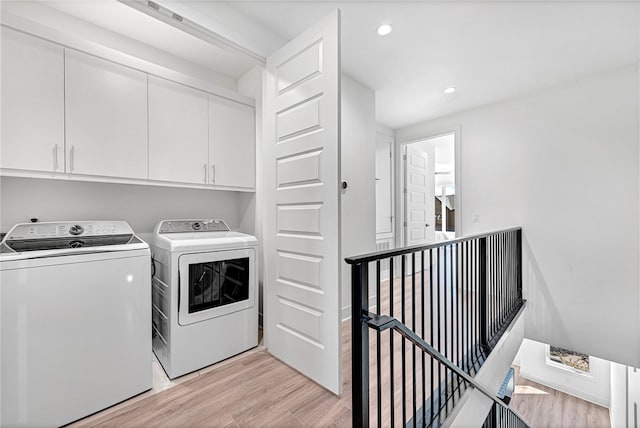 laundry area featuring light wood-type flooring, cabinets, and separate washer and dryer