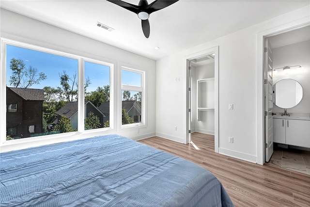 bedroom featuring hardwood / wood-style flooring, ensuite bath, sink, a spacious closet, and ceiling fan