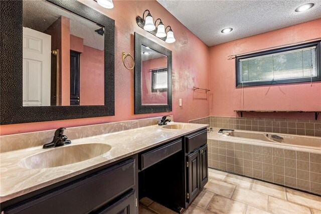 bathroom with vanity, a textured ceiling, and a relaxing tiled tub