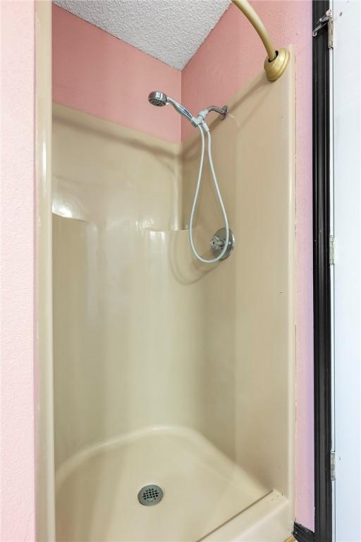 bathroom with a textured ceiling and walk in shower