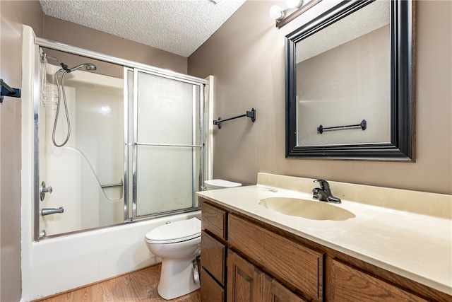 full bathroom featuring toilet, combined bath / shower with glass door, vanity, a textured ceiling, and wood-type flooring