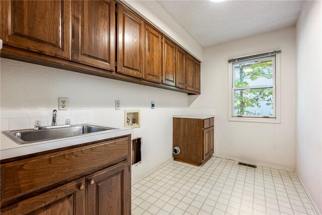 laundry area featuring hookup for an electric dryer, sink, washer hookup, cabinets, and a textured ceiling