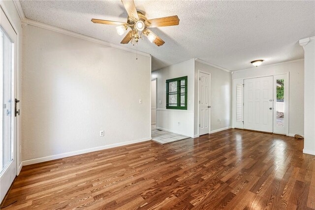 entrance foyer with a textured ceiling, ceiling fan, ornamental molding, and wood-type flooring