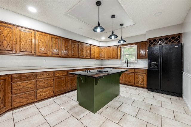 kitchen with a textured ceiling, decorative light fixtures, black appliances, a center island, and sink