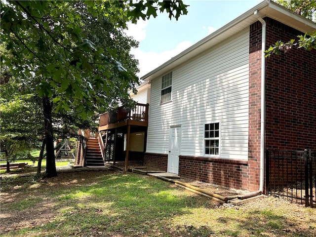 view of side of home with stairway, a deck, and brick siding