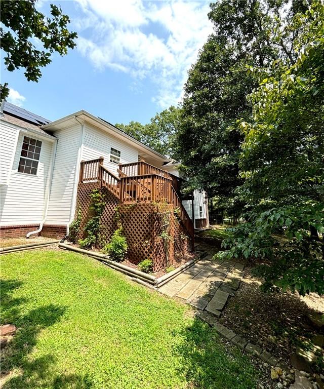 rear view of property featuring a yard, roof mounted solar panels, and a wooden deck