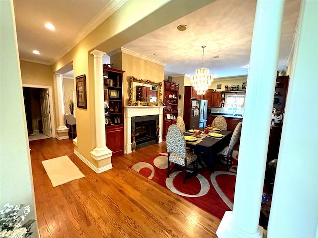 living room with ornate columns, ornamental molding, wood finished floors, and a high end fireplace