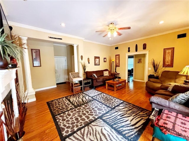 living area with crown molding, a fireplace with raised hearth, decorative columns, and wood finished floors