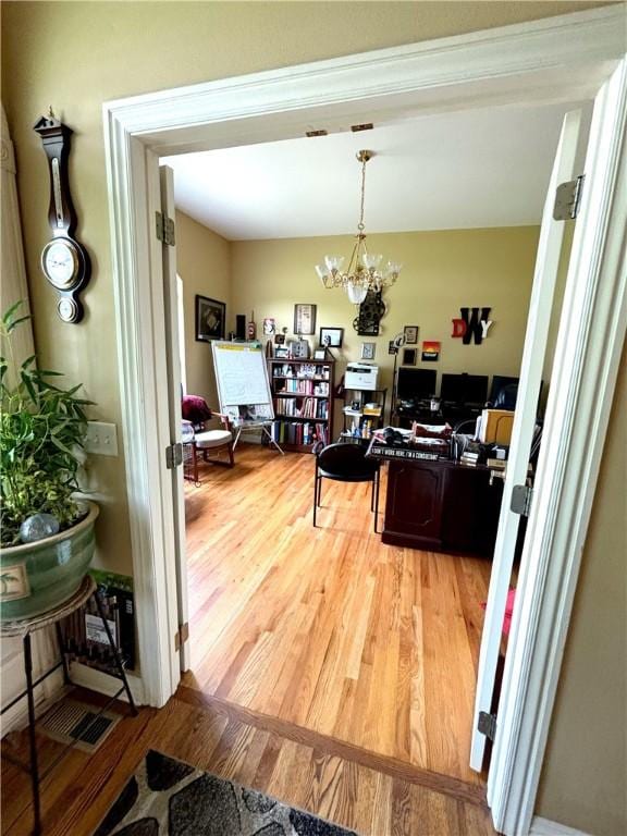 home office with an inviting chandelier and light wood-style flooring