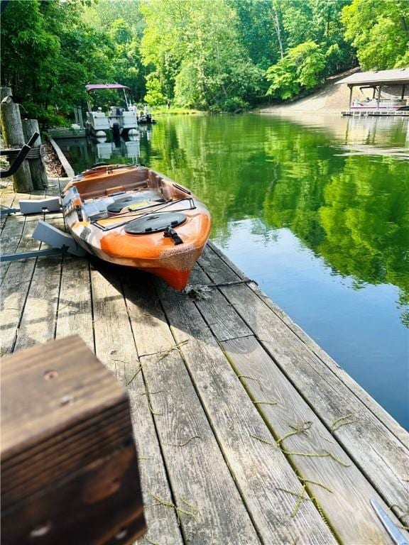 dock area featuring a wooded view and a water view