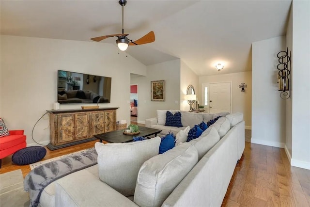 living area featuring lofted ceiling, ceiling fan, wood finished floors, and baseboards