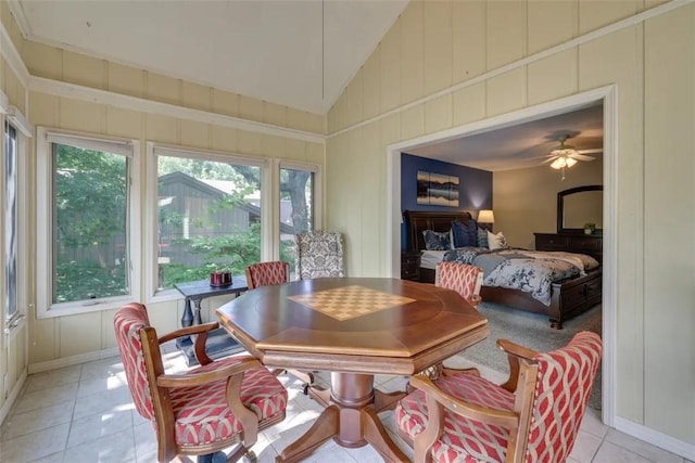 dining space featuring light tile patterned floors, lofted ceiling, a decorative wall, and baseboards