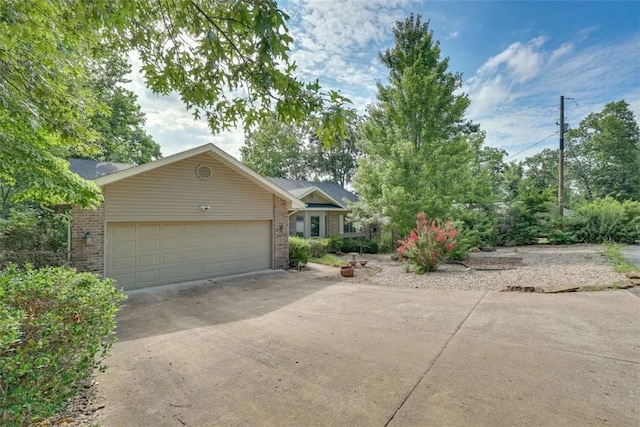 single story home featuring concrete driveway, a garage, and brick siding