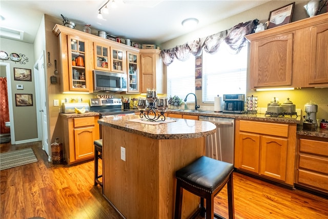 kitchen featuring appliances with stainless steel finishes, a kitchen island, light hardwood / wood-style floors, and a breakfast bar