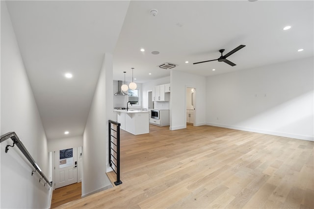 unfurnished living room featuring ceiling fan, sink, and light hardwood / wood-style flooring