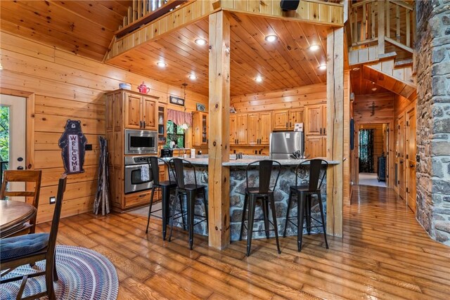 kitchen with a breakfast bar, stainless steel appliances, and wooden walls