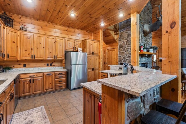 kitchen featuring wooden ceiling, light stone counters, stainless steel appliances, a kitchen island with sink, and a breakfast bar