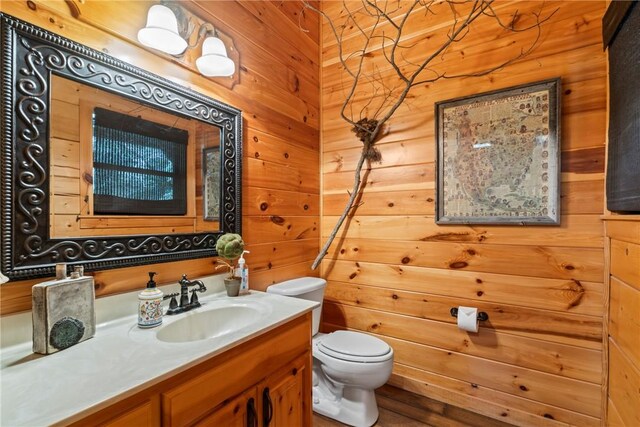 bathroom featuring vanity, toilet, and wood walls