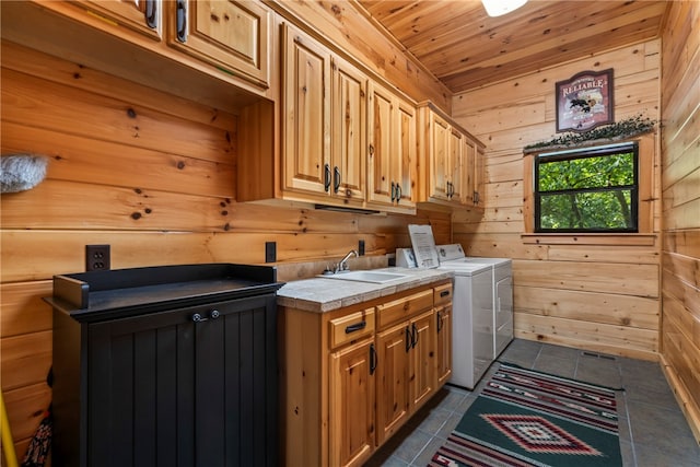 laundry room with cabinets, wood walls, washing machine and dryer, and dark tile patterned flooring