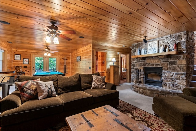 carpeted living room featuring a fireplace, wooden walls, ceiling fan, and wooden ceiling