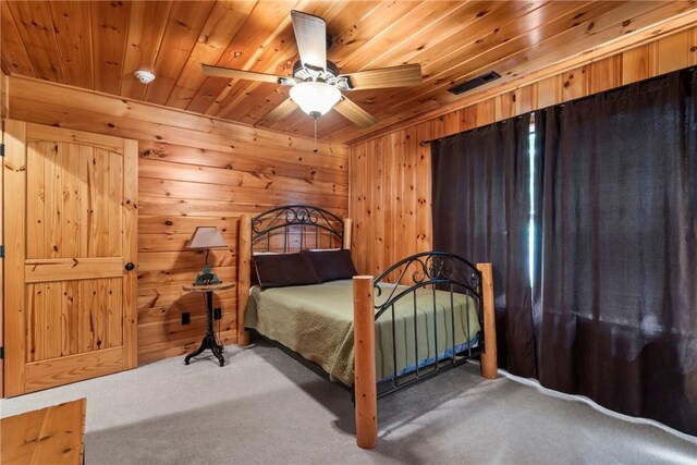 bedroom with ceiling fan, wood walls, carpet floors, and wooden ceiling