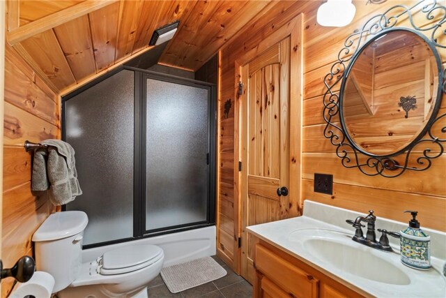 full bathroom featuring shower / bath combination with glass door, vanity, toilet, and wood walls