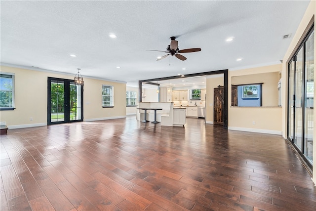 unfurnished living room featuring ceiling fan, dark hardwood / wood-style flooring, and a textured ceiling