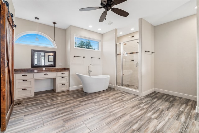 bathroom featuring plus walk in shower, hardwood / wood-style floors, ceiling fan, and vanity