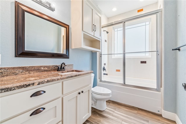 full bathroom featuring shower / bath combination with glass door, wood-type flooring, toilet, and vanity