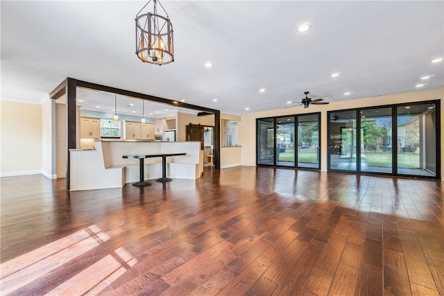 unfurnished living room featuring dark wood-type flooring and ceiling fan with notable chandelier