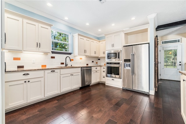 kitchen with sink, light stone countertops, appliances with stainless steel finishes, and dark hardwood / wood-style flooring