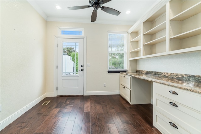 interior space with built in desk, ceiling fan, dark hardwood / wood-style floors, and ornamental molding