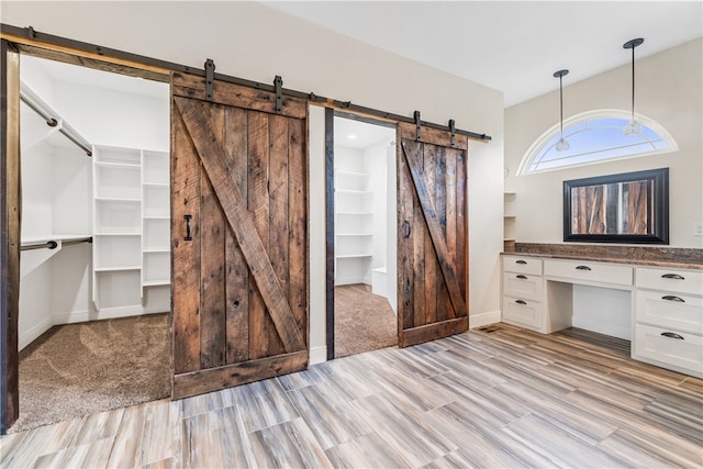 interior space with a barn door, light hardwood / wood-style flooring, and built in desk