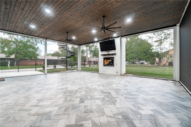 unfurnished sunroom featuring wood ceiling, a healthy amount of sunlight, and ceiling fan