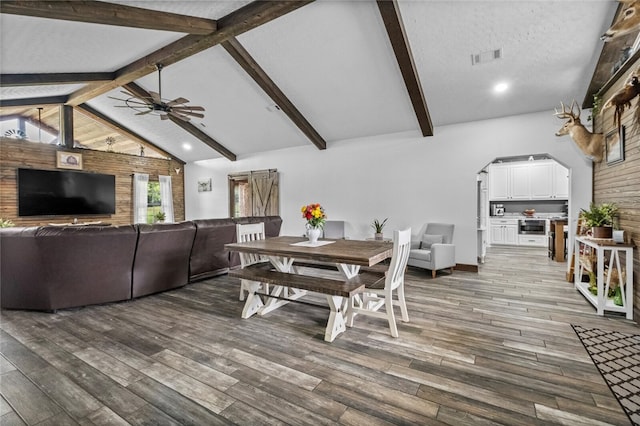 dining room with a textured ceiling, beamed ceiling, ceiling fan, and dark hardwood / wood-style floors