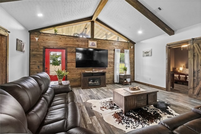 living room featuring hardwood / wood-style flooring, plenty of natural light, wood walls, and a barn door