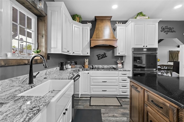 kitchen with custom exhaust hood, dark hardwood / wood-style flooring, light stone countertops, black electric cooktop, and white cabinets