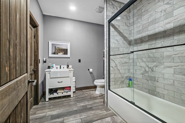 full bathroom featuring vanity, toilet, bath / shower combo with glass door, and wood-type flooring