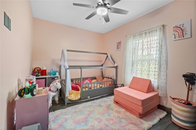 bedroom featuring a crib, hardwood / wood-style floors, and ceiling fan