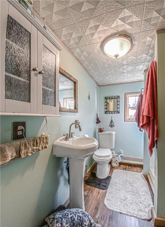 bathroom with toilet, ornamental molding, and hardwood / wood-style floors