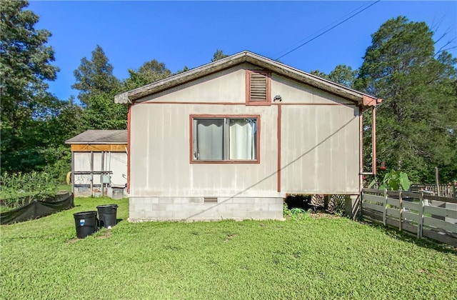 view of side of home with a lawn, fence, and crawl space