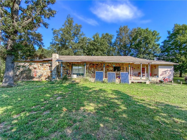 view of front of property featuring stone siding, a chimney, and a front lawn