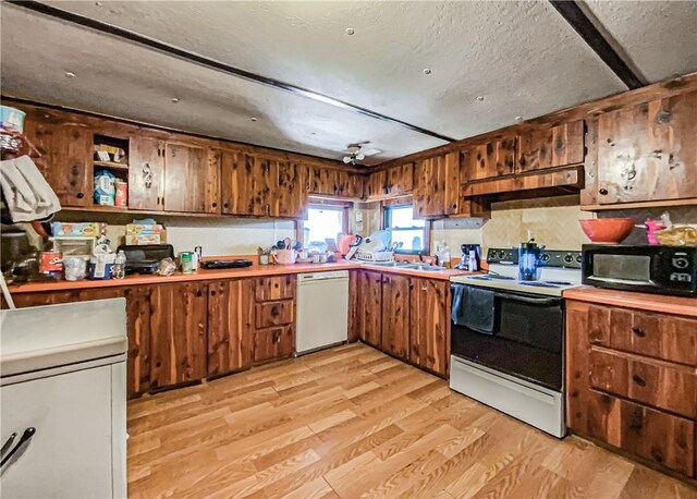 kitchen with a textured ceiling, sink, white appliances, and light hardwood / wood-style floors