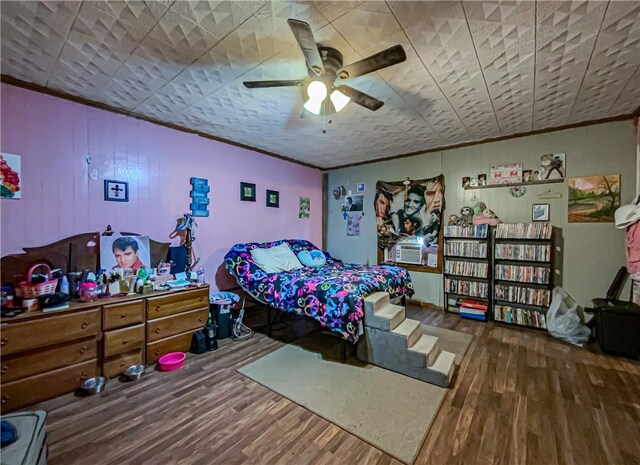 bedroom featuring ornamental molding, cooling unit, ceiling fan, and wood finished floors