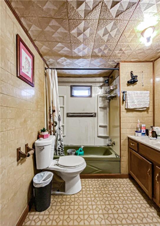 full bathroom featuring vanity, toilet, shower / tub combo, and tile walls