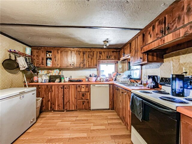 kitchen featuring light wood-type flooring, white appliances, sink, and a textured ceiling