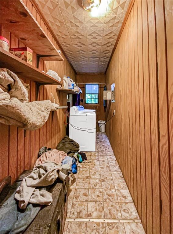 laundry room with washing machine and clothes dryer and wooden walls