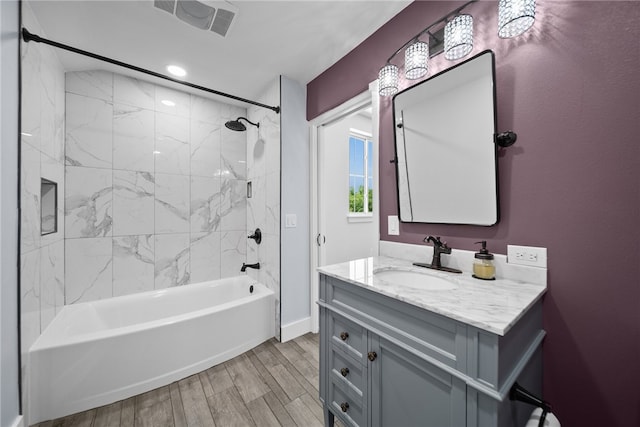 bathroom with wood-type flooring, tiled shower / bath combo, and vanity