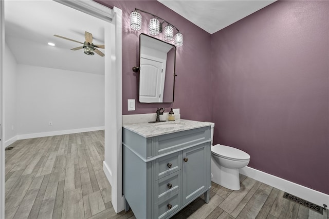 bathroom featuring vanity, toilet, hardwood / wood-style flooring, and ceiling fan